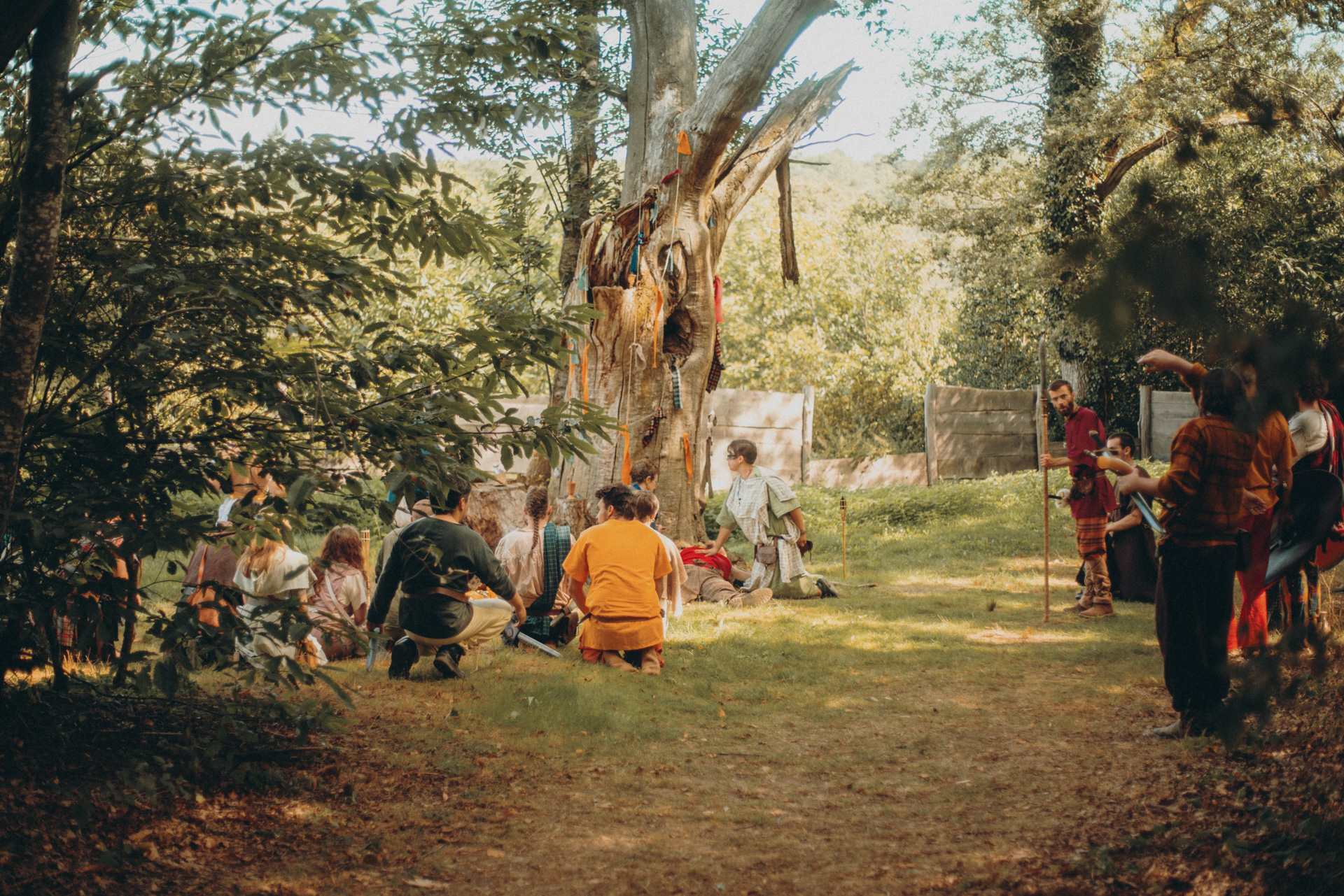 Costumed participants gathered beneath trees at a live action role-playing event