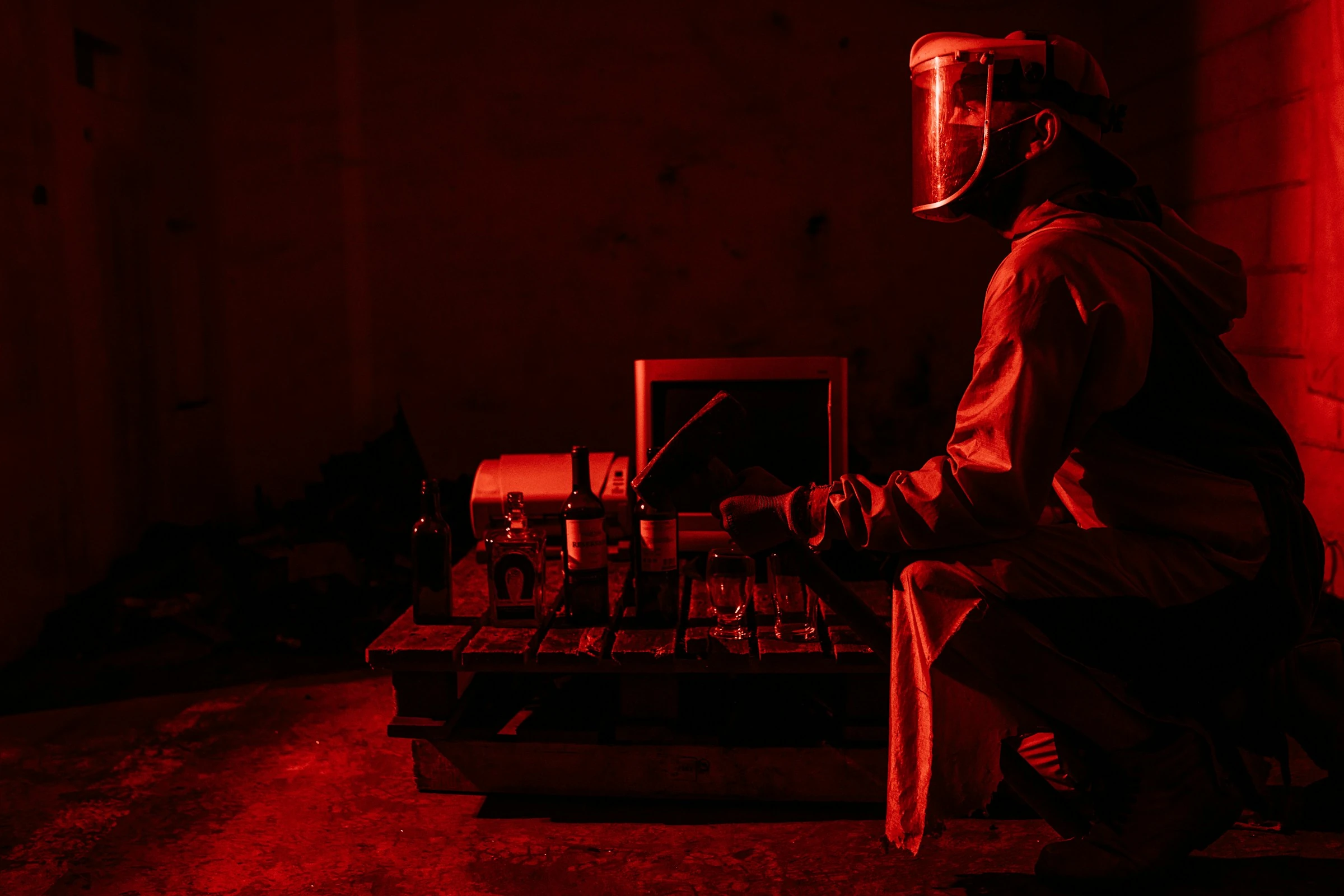 Participant wearing a face shield and coveralls beside breakable objects in a rage room