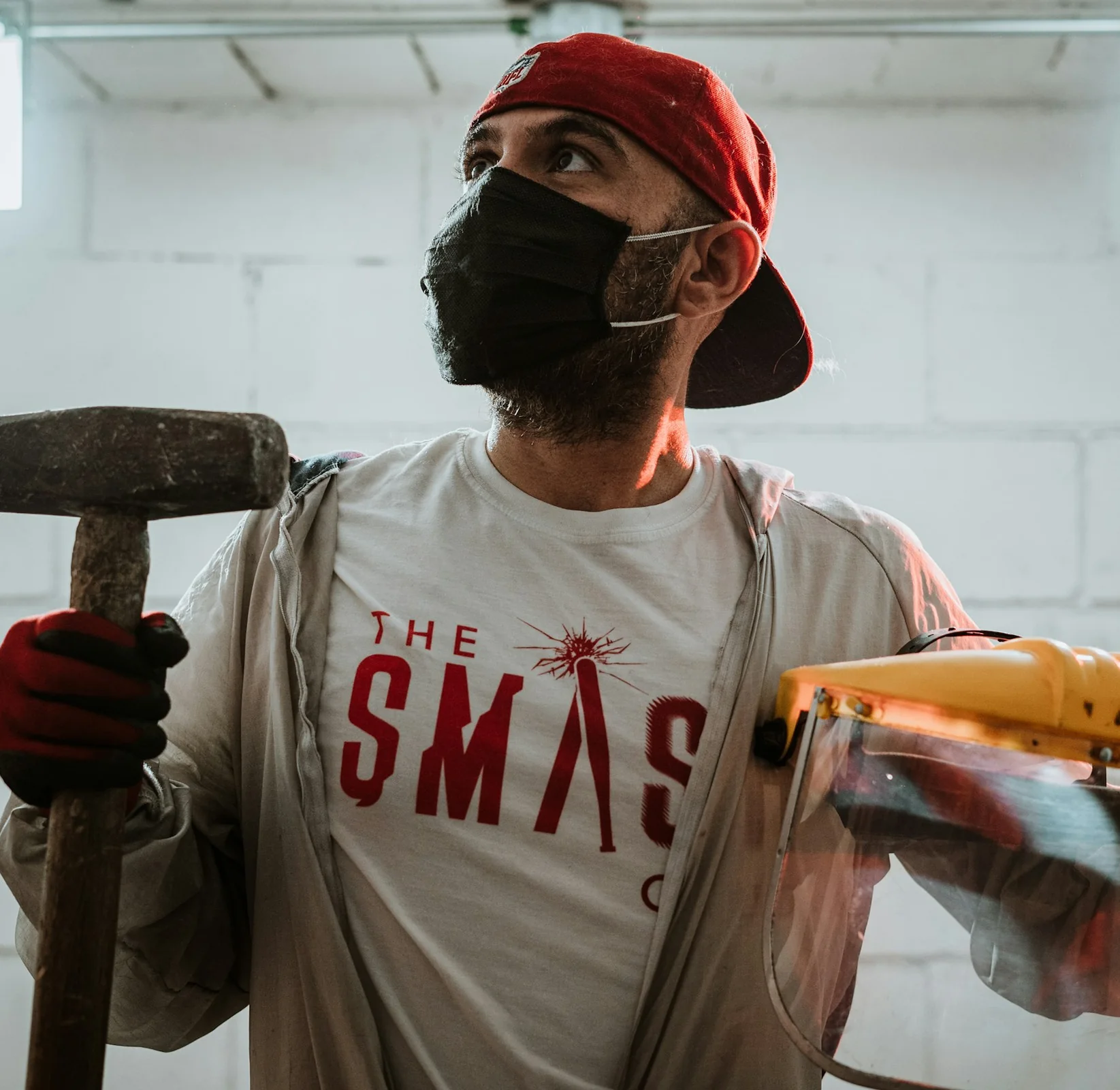 Rage-room participant holding a hammer and protective face shield