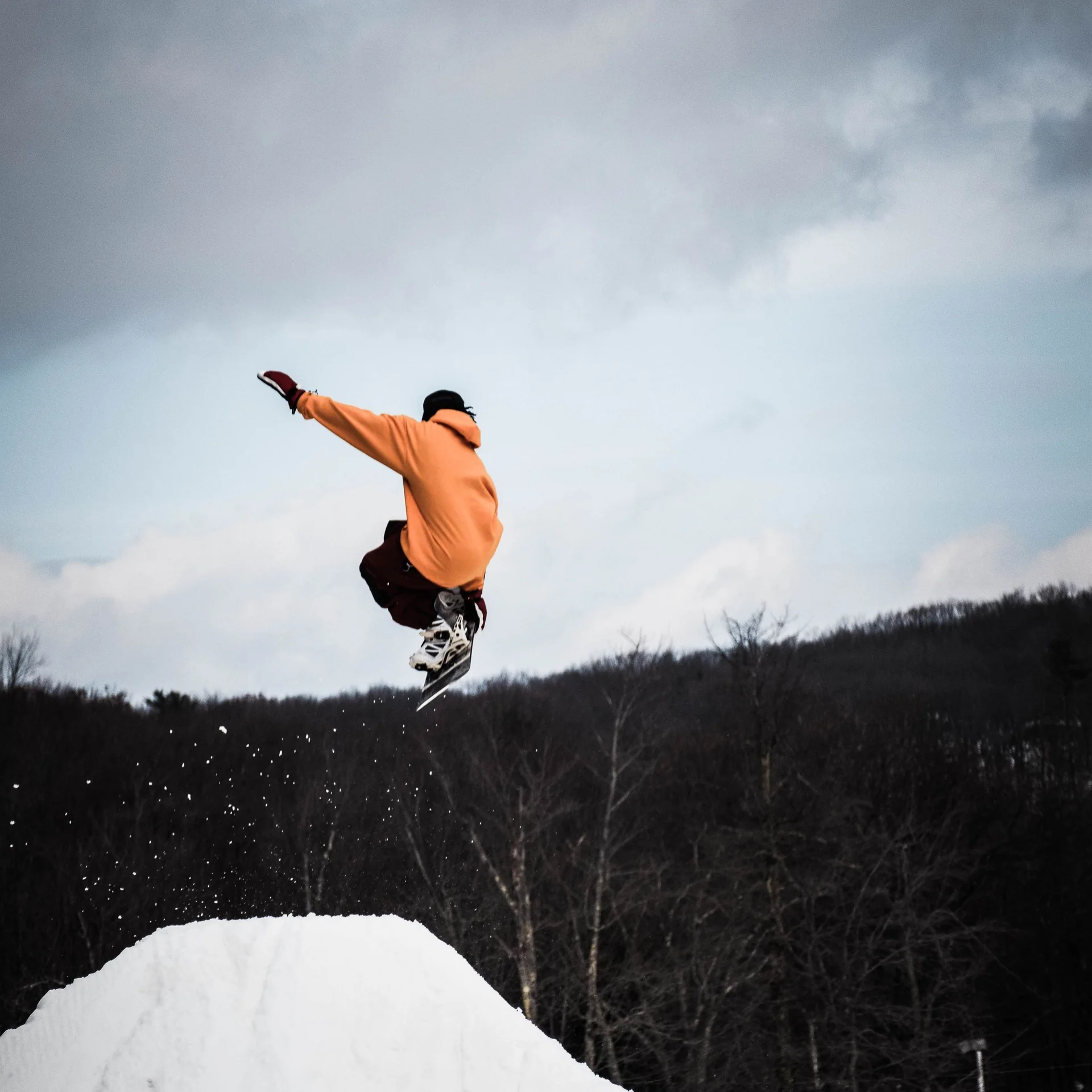 Snowboarder jumping above a snowy terrain-park ramp