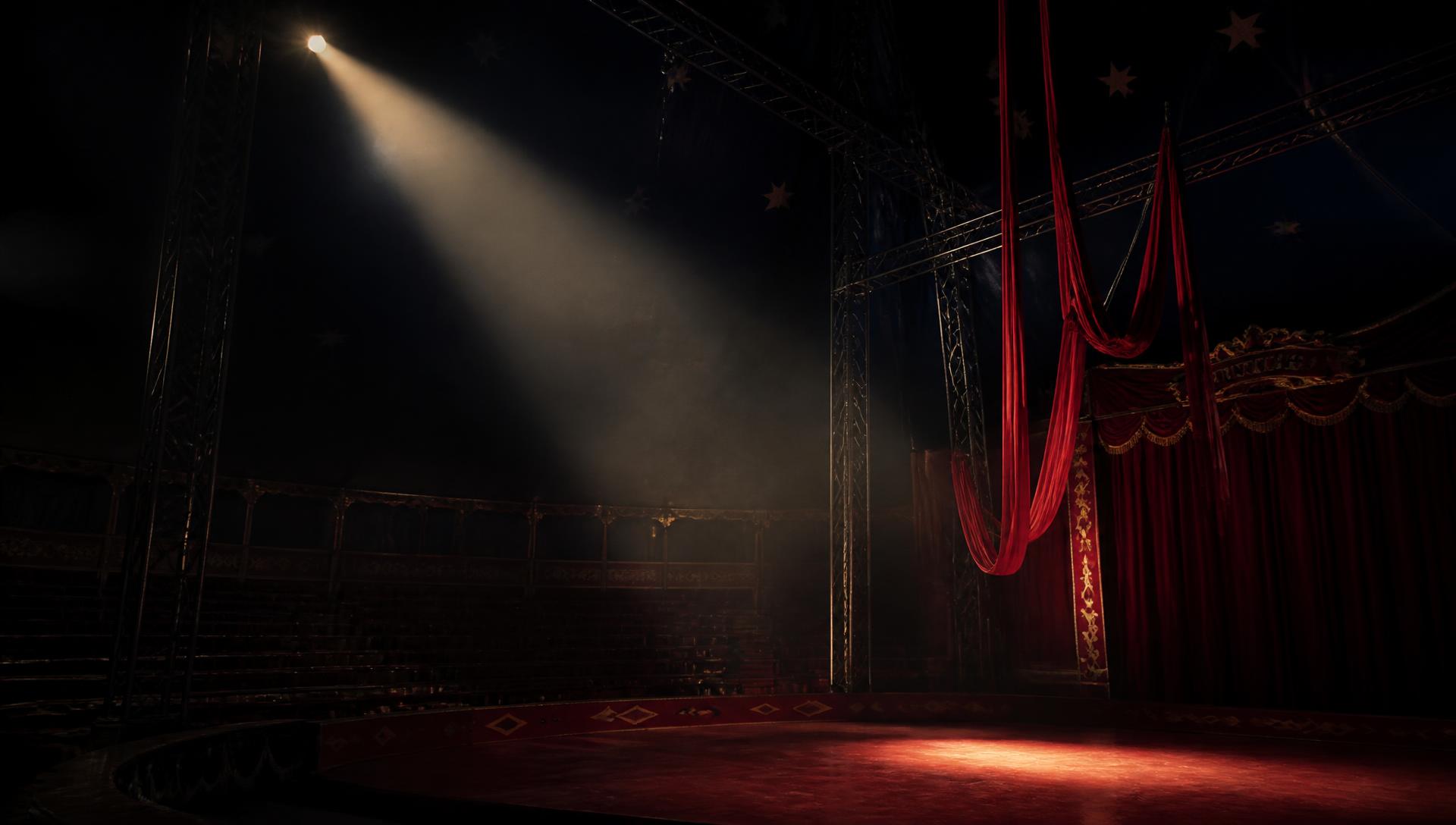 Rigging and trapeze suspended above an empty sawdust ring inside a striped circus big top with spotlights in haze